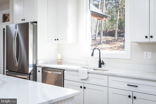 kitchen featuring white cabinetry, stainless steel appliances, sink, and light stone counters