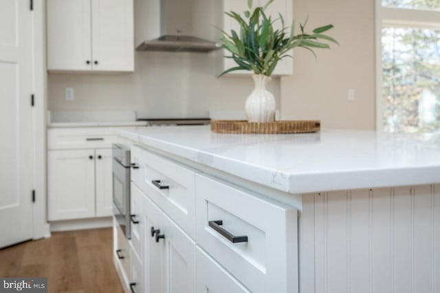 kitchen featuring stovetop, wall chimney range hood, white cabinets, and dark hardwood / wood-style flooring