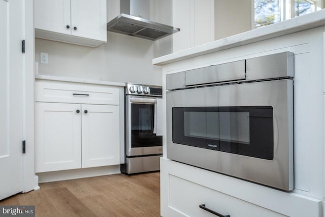 kitchen featuring white cabinetry, electric range, oven, and wall chimney range hood