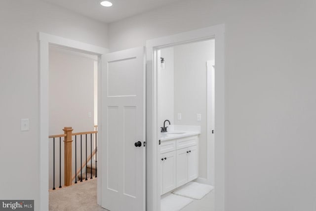 hallway with sink and light carpet