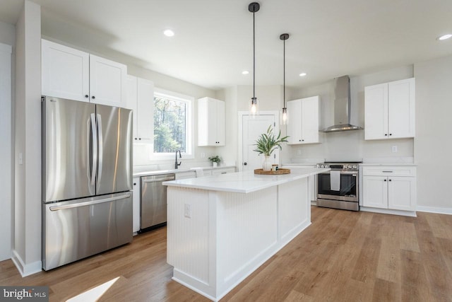 kitchen with white cabinetry, stainless steel appliances, wall chimney exhaust hood, and a kitchen island