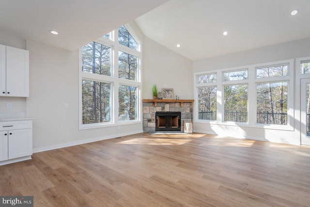 unfurnished living room with plenty of natural light, a stone fireplace, and light wood-type flooring