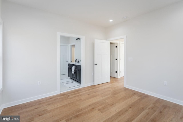 unfurnished bedroom with ensuite bath and light wood-type flooring