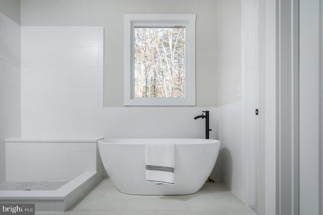 bathroom with a washtub and tile walls