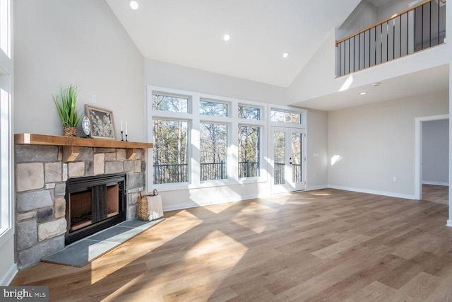 living room with high vaulted ceiling, a fireplace, and light hardwood / wood-style floors