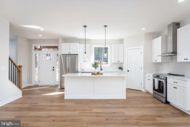 kitchen with white cabinetry, stainless steel appliances, a center island, decorative light fixtures, and wall chimney exhaust hood