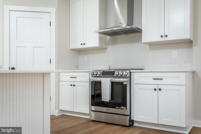 kitchen featuring white cabinets, stainless steel electric range, wall chimney exhaust hood, and hardwood / wood-style flooring