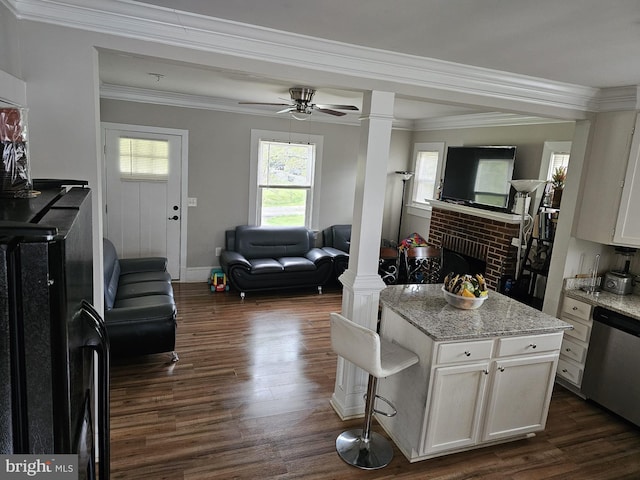 kitchen with light stone counters, dishwasher, decorative columns, and white cabinets