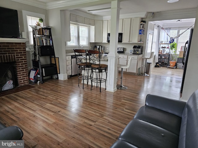 living room with a fireplace, decorative columns, and hardwood / wood-style floors