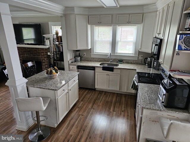 kitchen with a kitchen island, white cabinetry, sink, stainless steel appliances, and light stone countertops