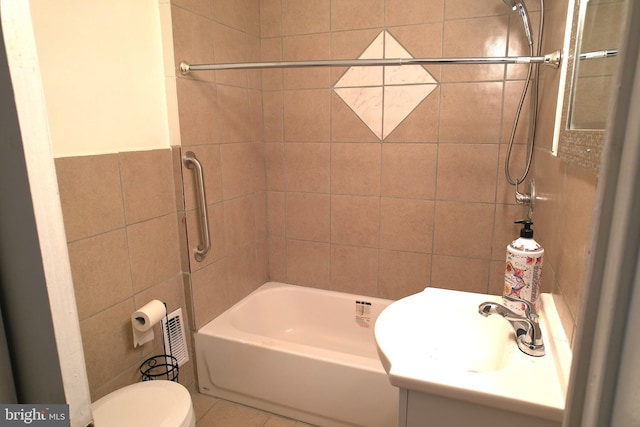 full bathroom with tiled shower / bath, sink, tile walls, tile patterned flooring, and toilet