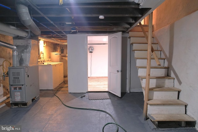 basement with water heater, heating unit, and washer and dryer