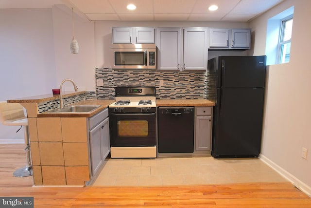 kitchen with pendant lighting, sink, gray cabinetry, black appliances, and kitchen peninsula