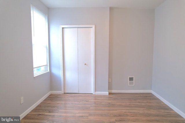 unfurnished bedroom with multiple windows, hardwood / wood-style flooring, and a closet