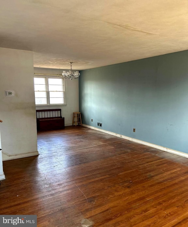 spare room with dark hardwood / wood-style floors and a chandelier