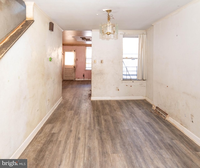 spare room with a notable chandelier, ornamental molding, and dark hardwood / wood-style floors