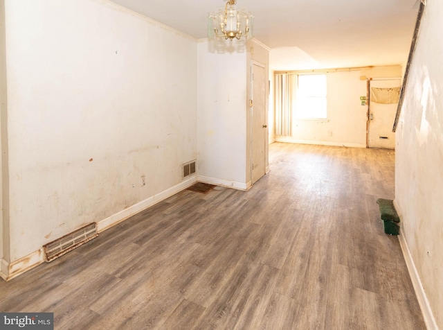 unfurnished room featuring crown molding, hardwood / wood-style flooring, and a chandelier