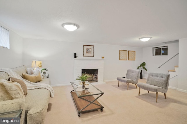 carpeted living area featuring stairway, a brick fireplace, and baseboards