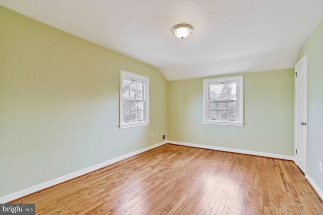 unfurnished room with hardwood / wood-style floors, vaulted ceiling, and baseboards