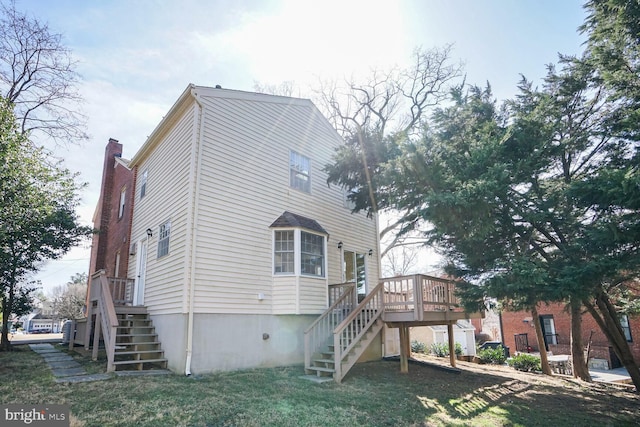 back of property featuring a lawn, a chimney, and stairs