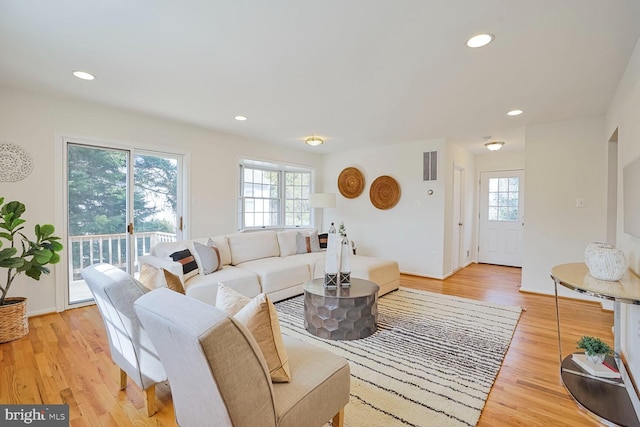 living room with visible vents, light wood-style flooring, and plenty of natural light