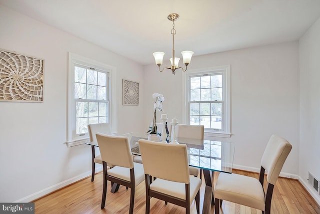 dining area featuring light wood-type flooring, baseboards, visible vents, and a chandelier