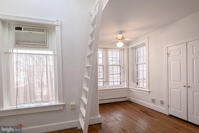 interior space featuring dark wood-type flooring, a baseboard radiator, and an AC wall unit