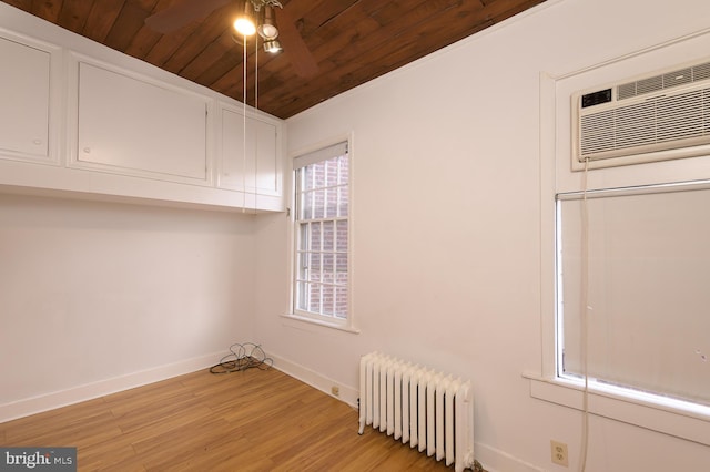 interior space with radiator, ceiling fan, a wall mounted air conditioner, light hardwood / wood-style floors, and wooden ceiling