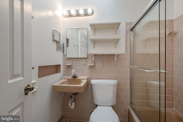 full bathroom featuring sink, enclosed tub / shower combo, tile walls, tasteful backsplash, and toilet