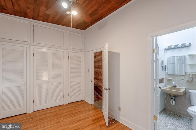 bedroom with sink, wood ceiling, light hardwood / wood-style flooring, tile walls, and connected bathroom