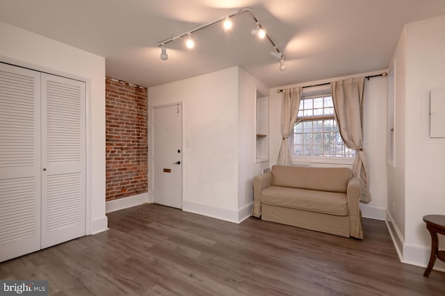 unfurnished room featuring dark hardwood / wood-style flooring and brick wall