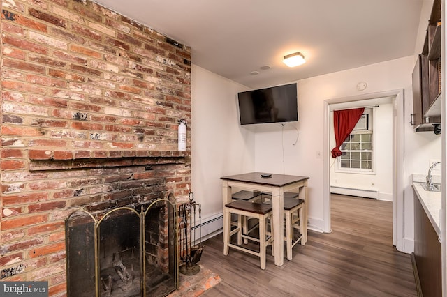 living room with a brick fireplace, dark wood-type flooring, and a baseboard radiator