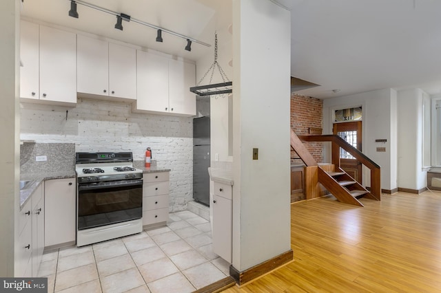 kitchen featuring gas stove, white cabinets, light hardwood / wood-style floors, and decorative light fixtures