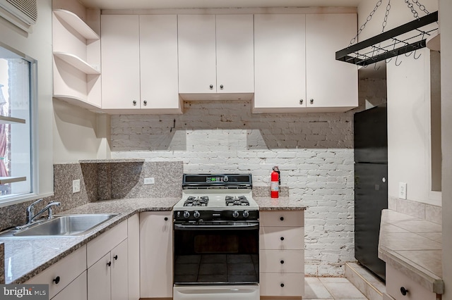 kitchen with white cabinetry, sink, light stone counters, and gas range oven