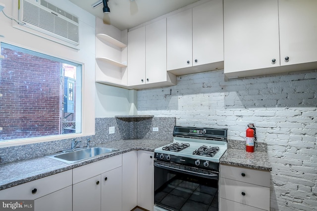 kitchen featuring white cabinetry, sink, a wall unit AC, and black gas range