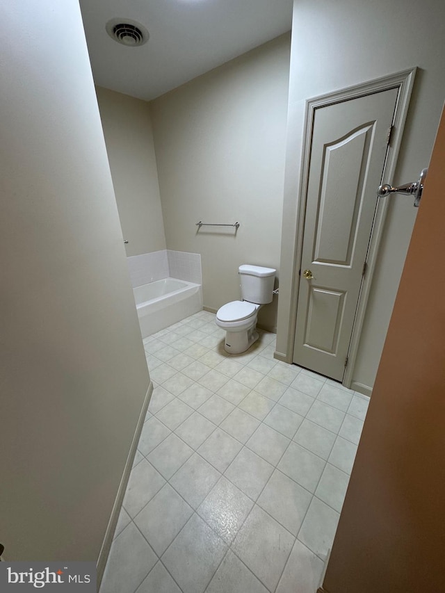 bathroom featuring tile patterned flooring, a tub, and toilet