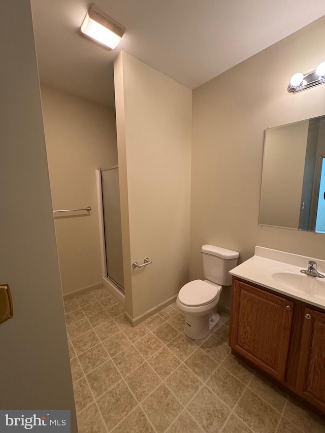 bathroom featuring vanity, toilet, and a shower with door