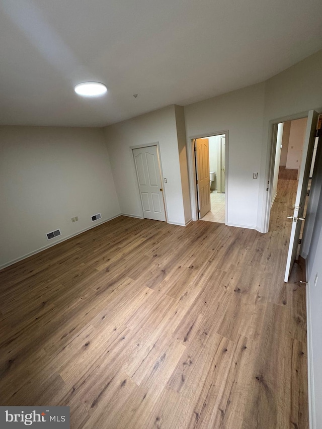 unfurnished bedroom featuring connected bathroom and light hardwood / wood-style floors