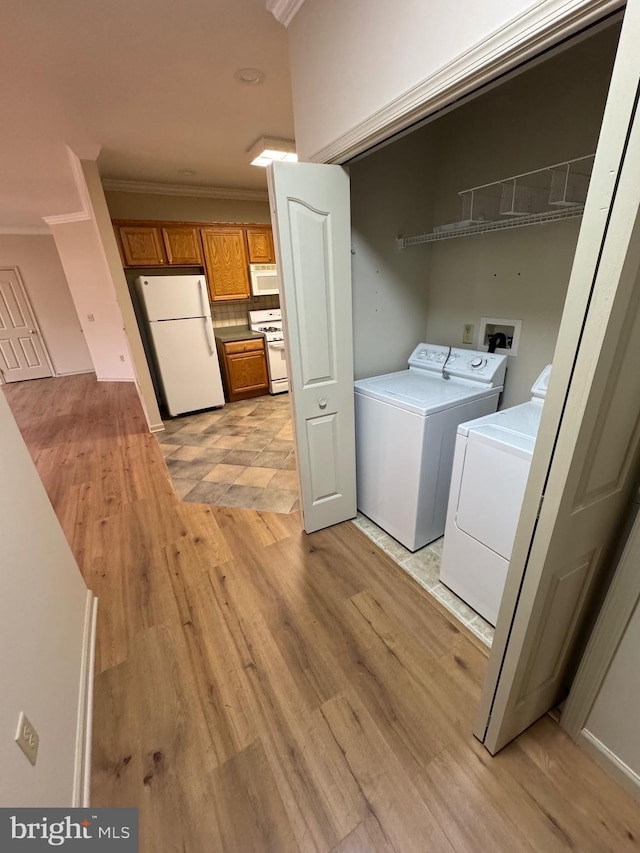 laundry room featuring ornamental molding, separate washer and dryer, and light hardwood / wood-style floors