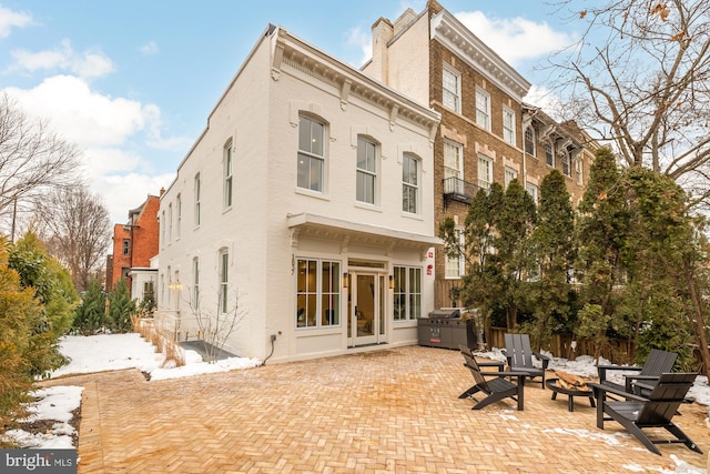 snow covered property featuring an outdoor fire pit and a patio area