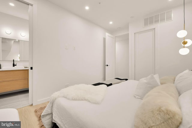 bedroom with sink and light hardwood / wood-style flooring