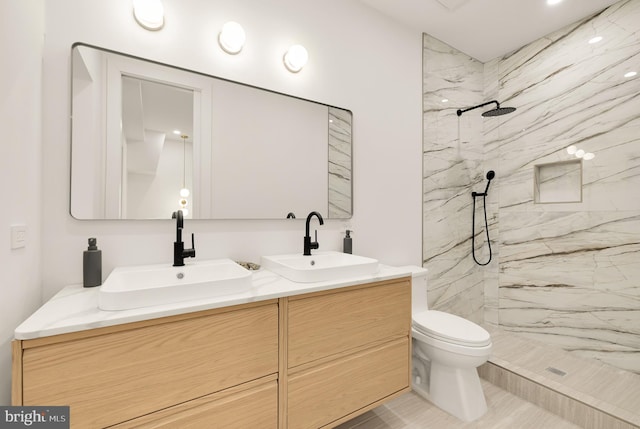 bathroom featuring vanity, toilet, and tiled shower