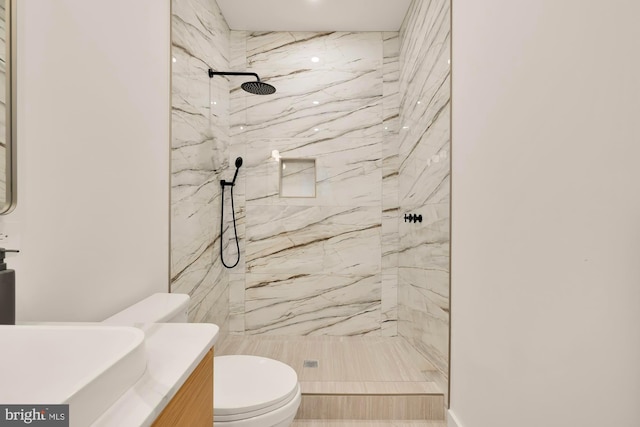 bathroom featuring vanity, a tile shower, and toilet