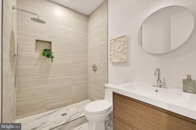 bathroom with vanity, tiled shower, and toilet