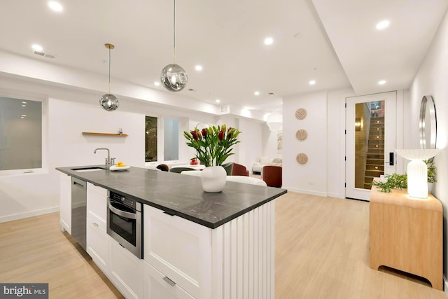 kitchen with sink, decorative light fixtures, a center island with sink, appliances with stainless steel finishes, and white cabinets