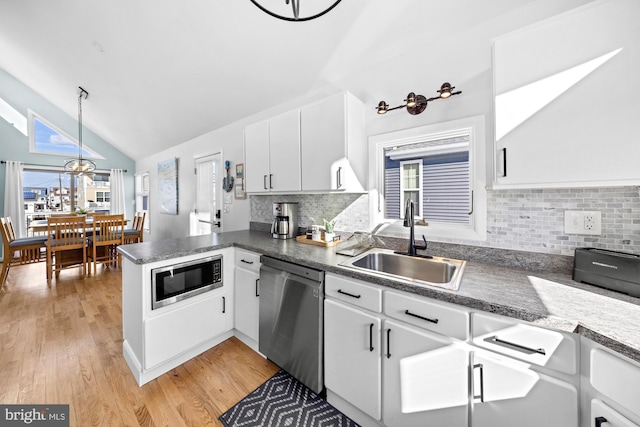 kitchen featuring pendant lighting, white cabinetry, sink, kitchen peninsula, and stainless steel appliances