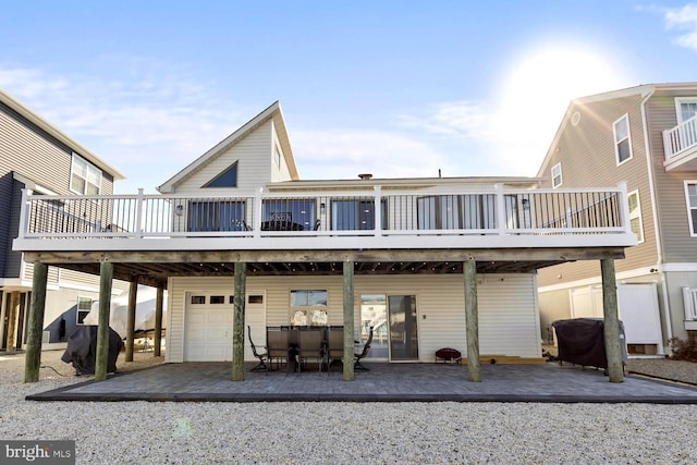 back of property featuring a garage, a deck, and a patio area