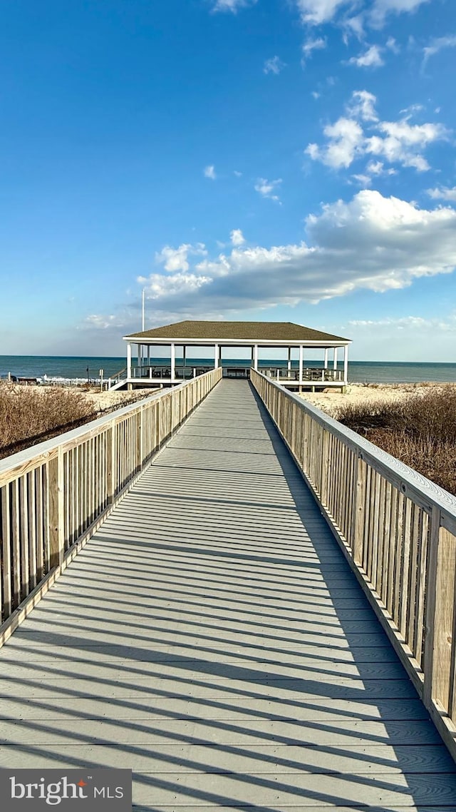 view of dock with a water view and a beach view