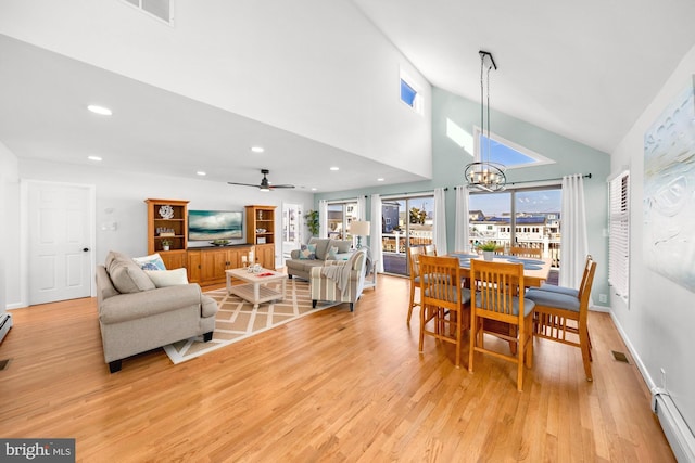 dining area featuring ceiling fan with notable chandelier, light wood-type flooring, high vaulted ceiling, and baseboard heating