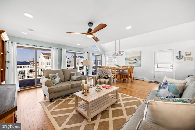 living room with ceiling fan, plenty of natural light, vaulted ceiling, and light hardwood / wood-style flooring